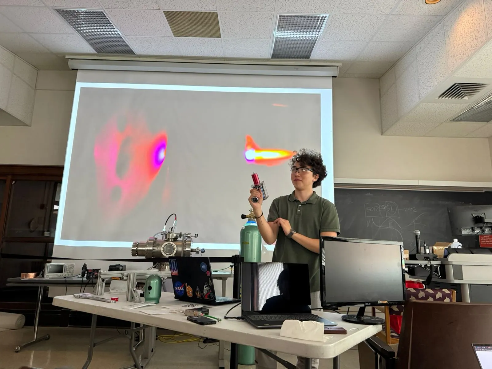 A member presenting a projected plasma simulation beside the hardware