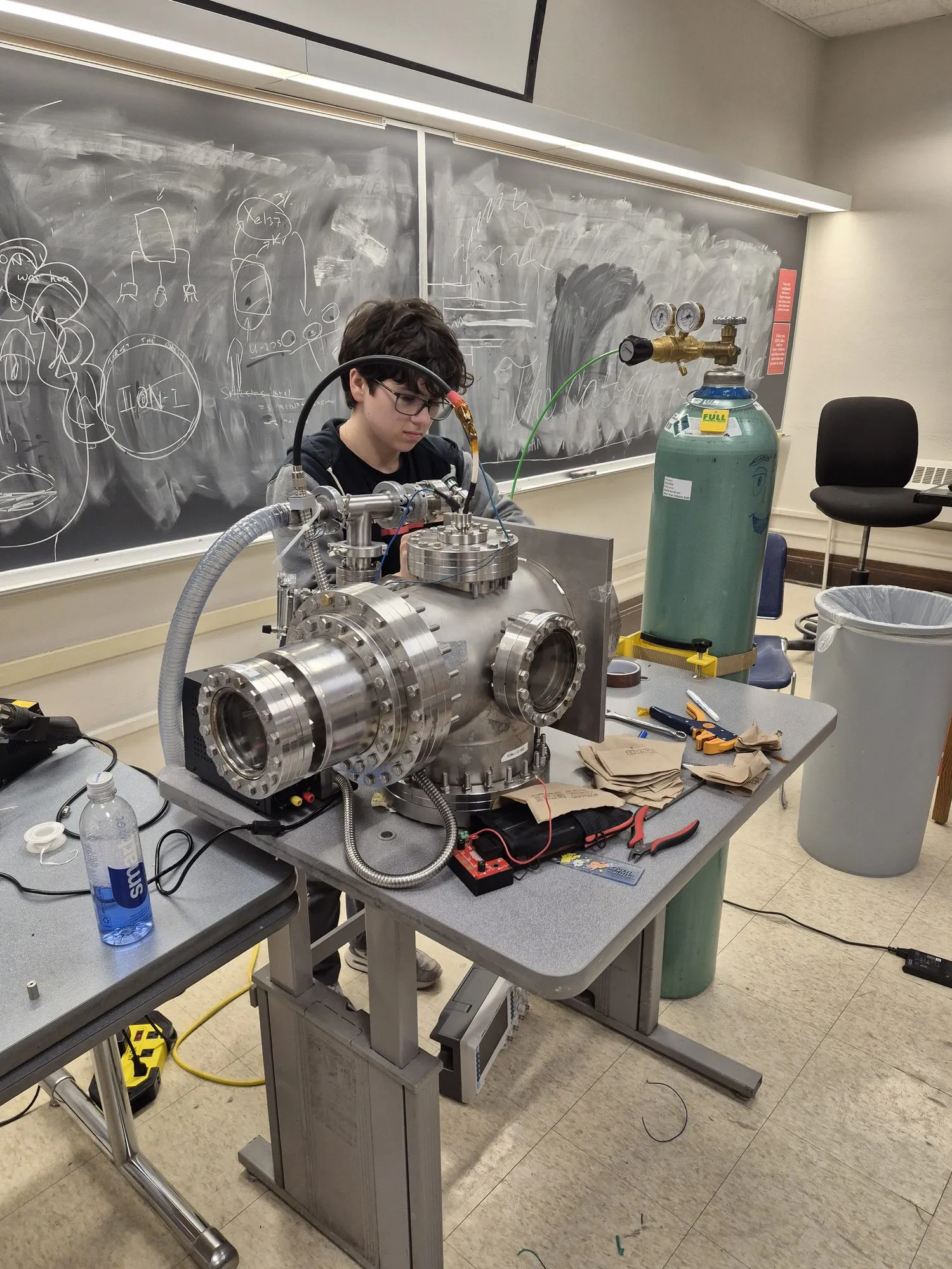 A member at the vacuum chamber in front of a chalkboard